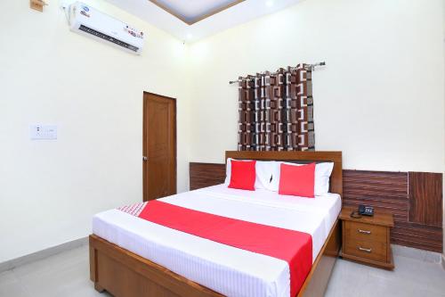 a bedroom with a bed with red and white sheets at OYO Flagship Hotel Amarpali in Baddi