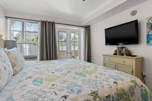 a bedroom with a large bed and a flat screen tv at 107F Barefoot Beach Resort in Clearwater Beach