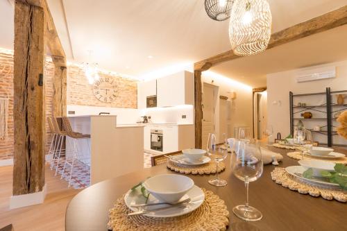 a dining room with a wooden table with plates and glasses at Ribera AC by Staynnapartments in Bilbao