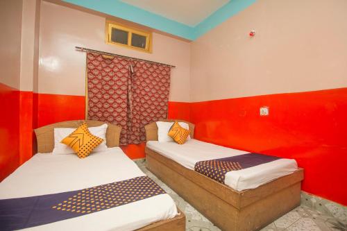 2 camas en una habitación con paredes rojas en OYO Hotel Chitra en Alīpur Duār