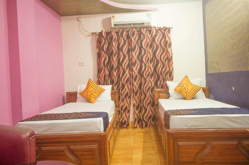 Habitación con 2 camas y cortina en OYO Hotel Chitra en Alīpur Duār