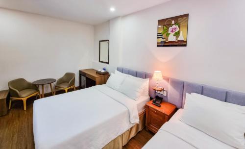a room with two beds and a table and chairs at Xavia Hotel Quy Nhơn in Quy Nhon