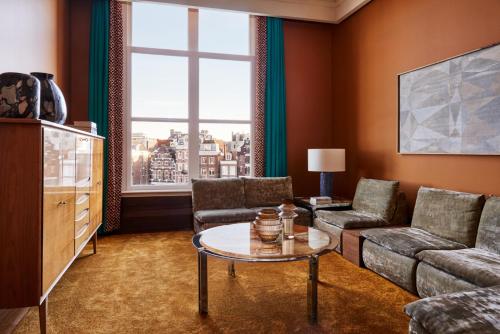 a living room with a couch and a table at De L’Europe Amsterdam – The Leading Hotels of the World in Amsterdam