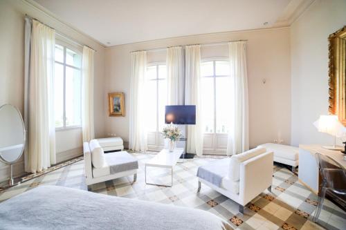 a bedroom with white furniture and a tv and windows at Château de Valmy - Chambres d'hôtes in Argelès-sur-Mer