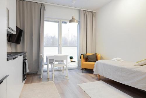 ein Schlafzimmer mit einem Bett, einem Tisch und einem Stuhl in der Unterkunft Forenom Serviced Apartments Espoo Saunalahti in Espoo