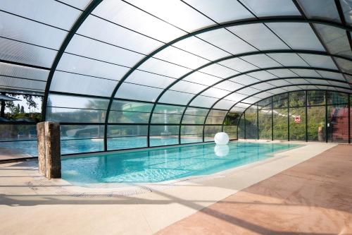 an indoor swimming pool with a glass ceiling at Camping maeva Escapades Le Domaine Aramis in Marsan