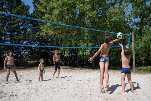 a group of young boys playing volleyball on the beach at Camping maeva Escapades Le Domaine Aramis in Marsan