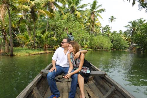 a man and woman sitting on a boat in the water at The Quilon Beach Hotel and Convention Center in Kollam