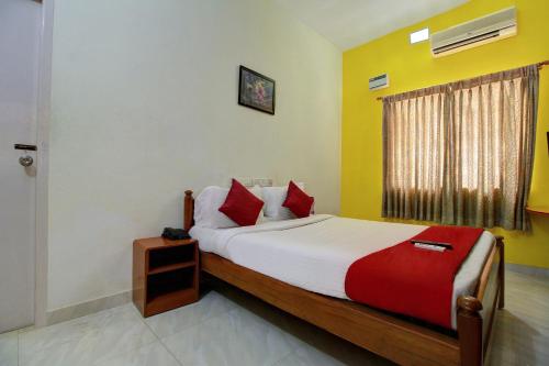 sypialnia z łóżkiem z czerwoną i białą pościelą oraz oknem w obiekcie Infosys Thoraipakkam Near Ecr Beach w mieście Ćennaj