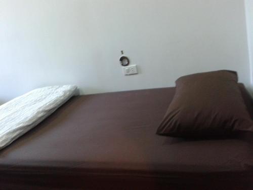 a bed with a brown pillow in a room at Phuket Sunny Hostel in Phuket Town