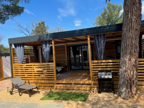 a large wooden cabin with a tree at La Mer Mobil Home in Biograd na Moru