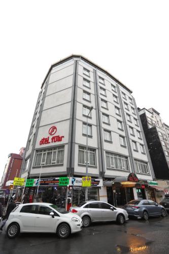 un edificio blanco alto con coches estacionados frente a él en Fuar Hotel, en Estambul