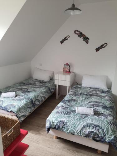 a room with two beds and a table and a bedskirts at MAISON AU COEUR DE LA PETITE CITE DE CARACTERE in Malestroit