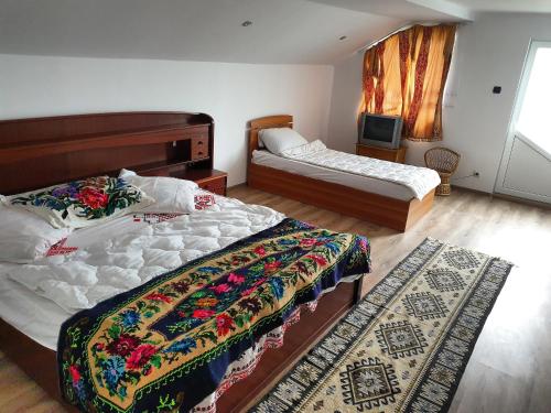 a bedroom with two beds and a rug at Casa Roxana in Vişeu de Mijloc