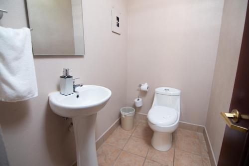 a white bathroom with a sink and a toilet at Hotel Lavas Tacotal in Fortuna