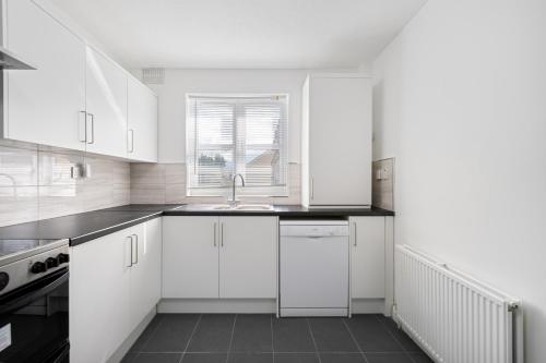 a white kitchen with white cabinets and a sink at Roomy 3 bedroom house, 2 baths in Edgware