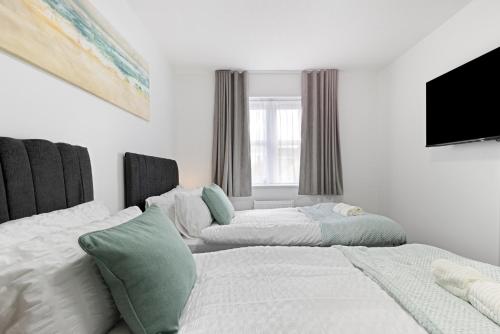 a bedroom with two beds and a flat screen tv at Roomy 3 bedroom house, 2 baths in Edgware