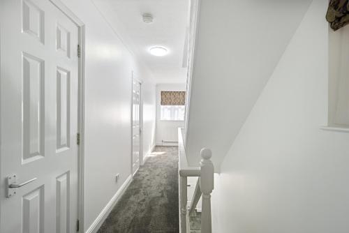 um corredor com paredes brancas e uma porta em Roomy 3 bedroom house, 2 baths em Edgware