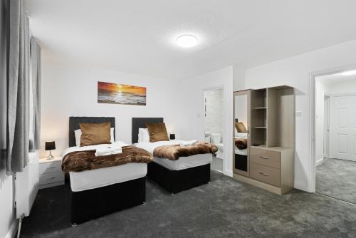 een witte slaapkamer met 2 bedden en een kast bij Roomy 3 bedroom house, 2 baths in Edgware