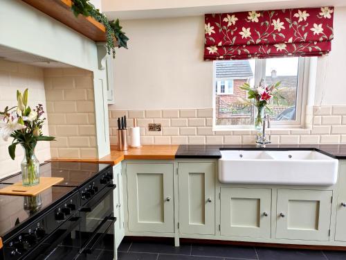 a kitchen with a white sink and a window at Grove House in Egremont