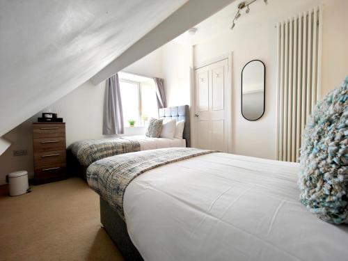 a bedroom with two beds and a mirror at Grove House in Egremont