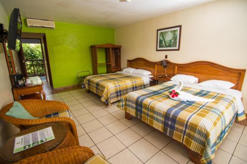a hotel room with two beds and a chair at Hotel Lavas Tacotal in Fortuna