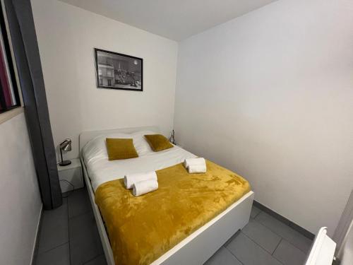 ein kleines Schlafzimmer mit einem Bett mit einer gelben Decke in der Unterkunft Dube YourHostHelper in Caen