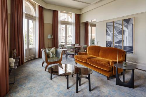 a living room with a couch and chairs and tables at De L’Europe Amsterdam – The Leading Hotels of the World in Amsterdam