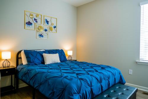 a bed with a blue comforter in a bedroom at Completely Renovated - The Art Deco Retreat in Durham