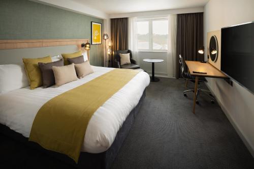 a hotel room with a large bed and a desk at Holiday Inn Oxford by IHG in Oxford