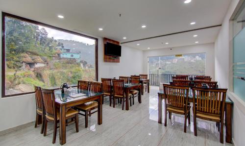 a restaurant with wooden tables and chairs and a large window at Treebo Down Town, Dalhousie in Dalhousie
