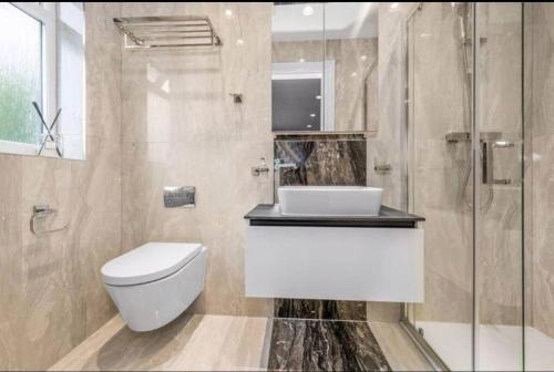 a bathroom with a toilet and a sink and a shower at Modern and spacious, family house. in Luton