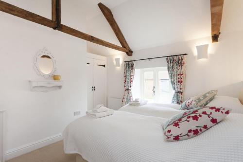 a white bedroom with two beds and a mirror at Harvey Cottage in Barney