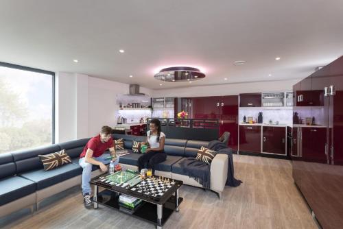 two people sitting on a couch in a living room at For Students Only Ensuite Bedrooms with Shared Kitchen at Triumph House in Nottingham in Nottingham