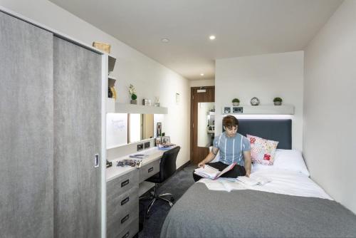 For Students Only Ensuite Bedrooms with Shared Kitchen at Triumph House in Nottingham في نوتينغهام: صبي صغير يجلس على سرير في غرفة النوم