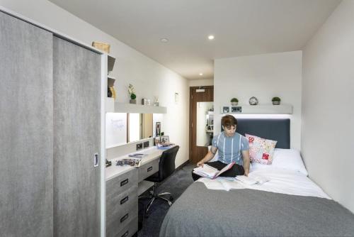 a young boy sitting on a bed in a bedroom at For Students Only Ensuite Bedrooms with Shared Kitchen at Triumph House in Nottingham in Nottingham