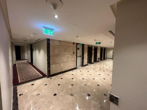 Emaar Elite Al Madina Hotel في المدينة المنورة: ممر فارغ في مبنى عليه علامة خضراء على الحائط