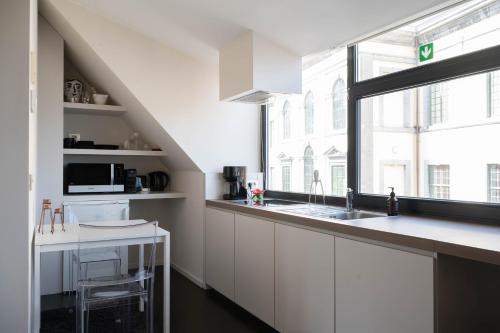 a white kitchen with a sink and a window at Designflats Gent in Ghent