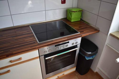 a kitchen with a stove and a sink and a trash can at Ferienwohnung Am Steigerwaldrand in Sugenheim