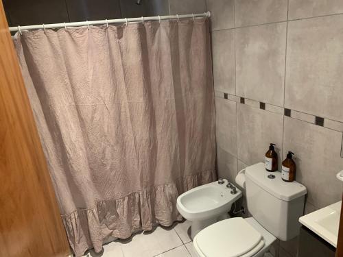 a bathroom with a toilet and a shower curtain at Luminoso monoambiente en Rosario in Rosario