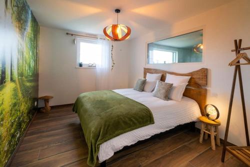 a bedroom with a large bed with a green blanket at La Clé du Bonheur sauna jacuzzi hammam massages 