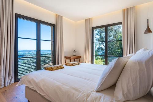 - une chambre avec un grand lit blanc et de grandes fenêtres dans l'établissement Villa Carpe Diem, à Grimaud