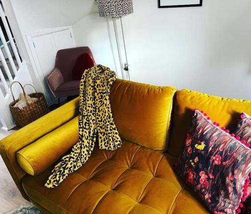 Un sofá amarillo con una manta de leopardo. en Luxury 2 bed cottage in the centre of Melbourne en Melbourne