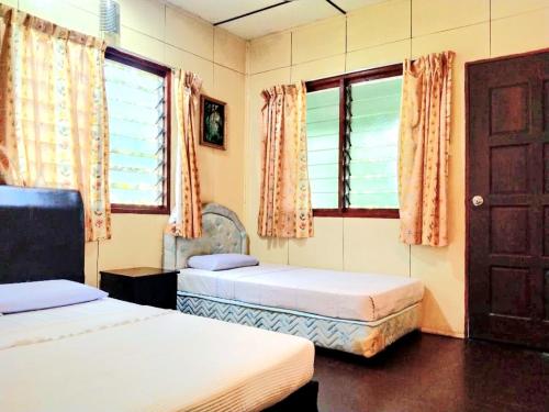 um quarto com 2 camas, uma porta e janelas em Sukau Backpackers B&B em Sukau