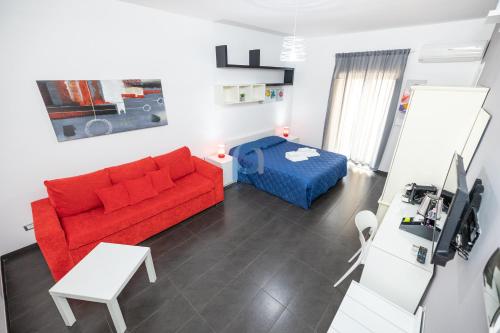 a living room with a red couch and a bed at Il Vittoria - Self Check in in Lascari