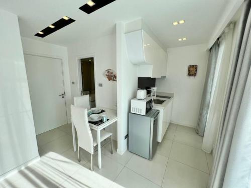 a small white kitchen with a table and a stove at COOL VIEW Studio in CCR Condo in Pattaya Central