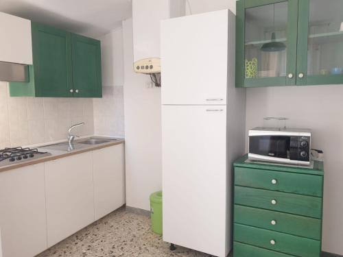 a kitchen with green and white cabinets and a microwave at SENZATESTA 2 in Osimo