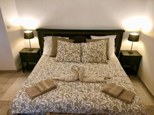 - 2 serviettes de cygne sur un lit avec 2 oreillers dans l'établissement Ulysse, Appartement Spacieux au Centre Historique d'Uzès en rez-de-chaussée avec extérieur, proche parking des Marroniers, à Uzès