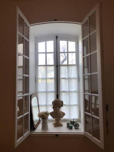 une fenêtre avec un miroir et un vase sur un rebord de fenêtre dans l'établissement Ulysse, Appartement Spacieux au Centre Historique d'Uzès en rez-de-chaussée avec extérieur, proche parking des Marroniers, à Uzès