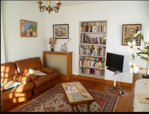 una sala de estar con un sofá de cuero marrón y estanterías de libros en Maison sur Rhue, en Égliseneuve-dʼEntraigues
